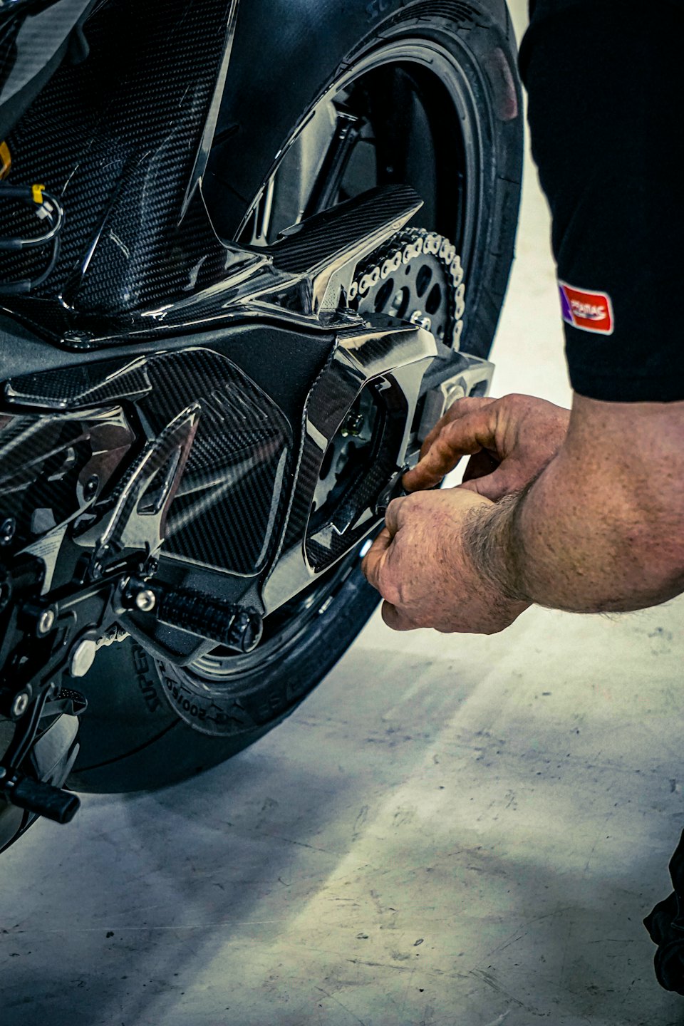 Un meccanico regola la catena e il pignone di una moto.